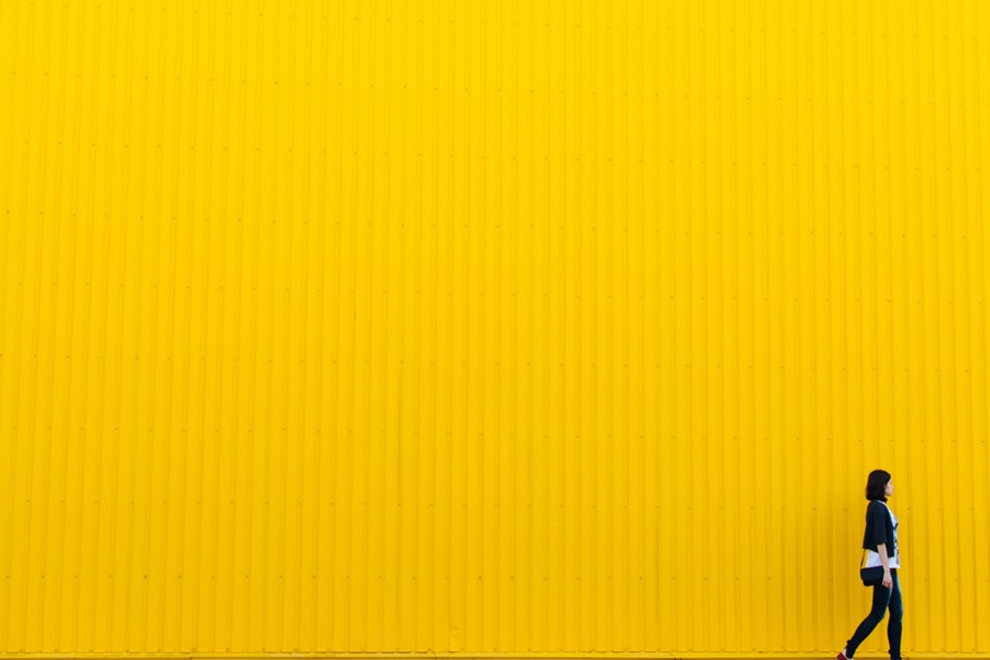 Woman walking past yellow wall