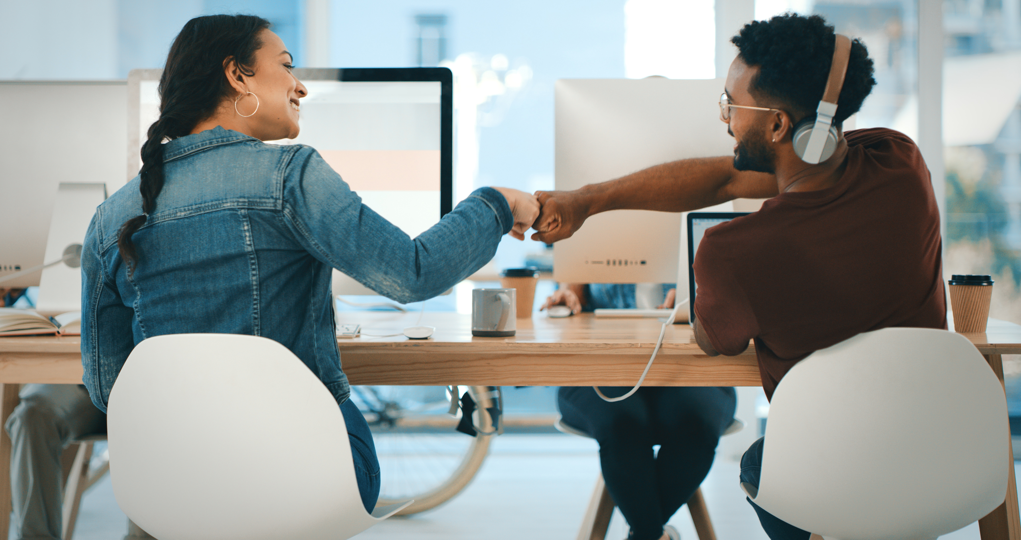 Two colleagues at work fist bumping