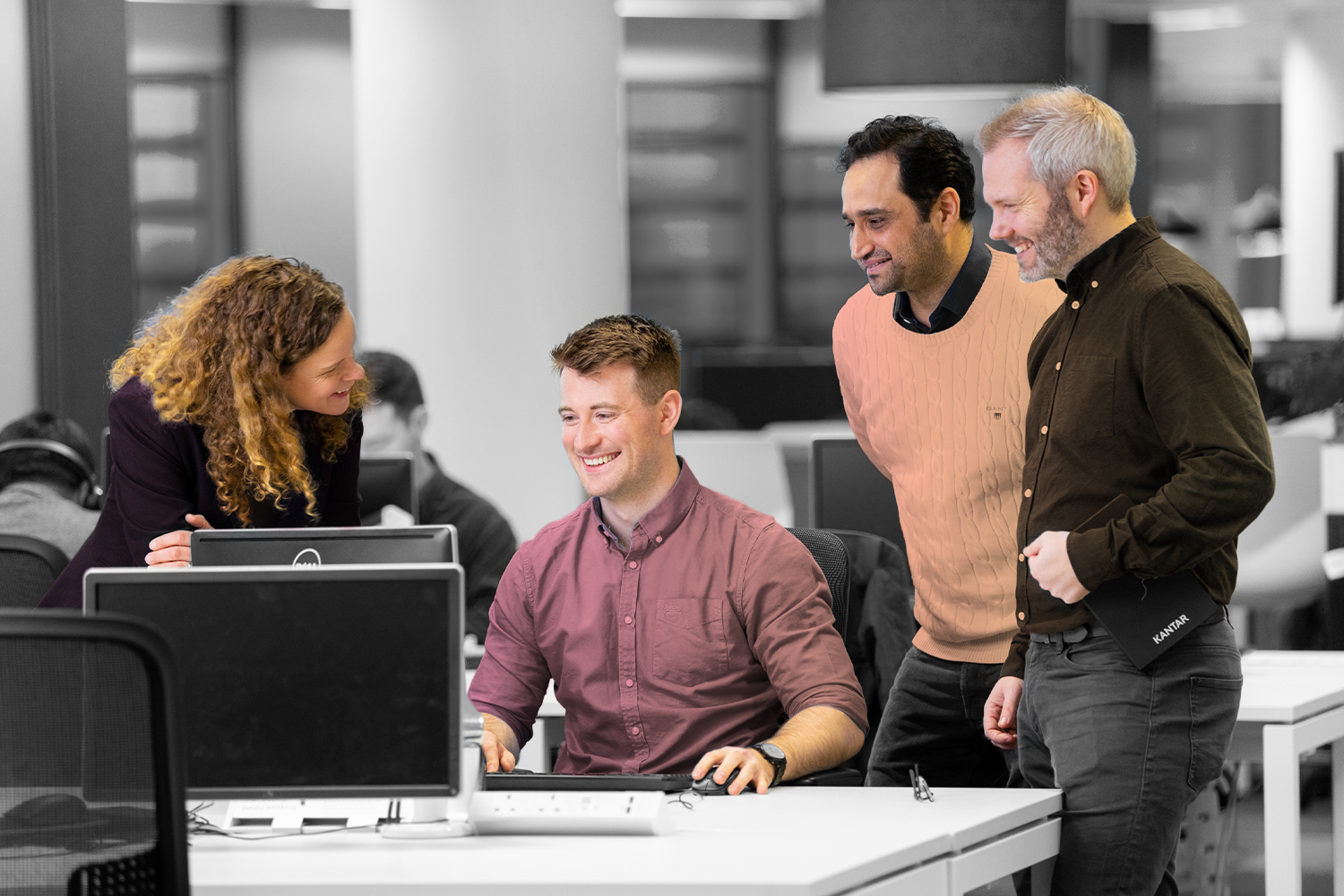 Four colleagues discussing work at a computer together.  