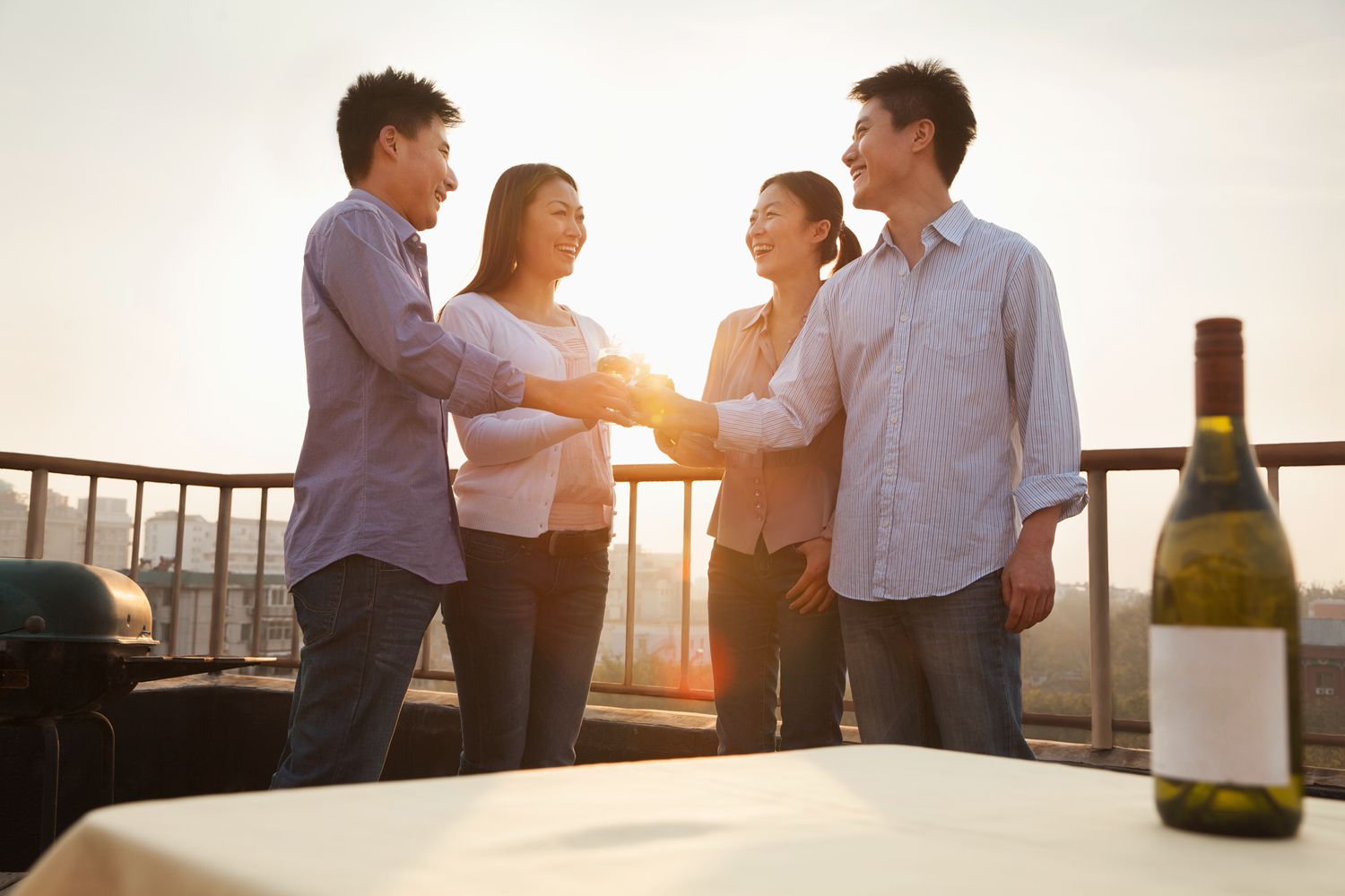 Group of Friends Toasting Each Other on Rooftop at Sunset